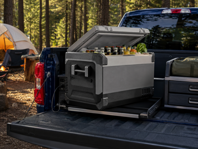 Rugged electric camping cooler open in the organized bed of a blue Ford F-150